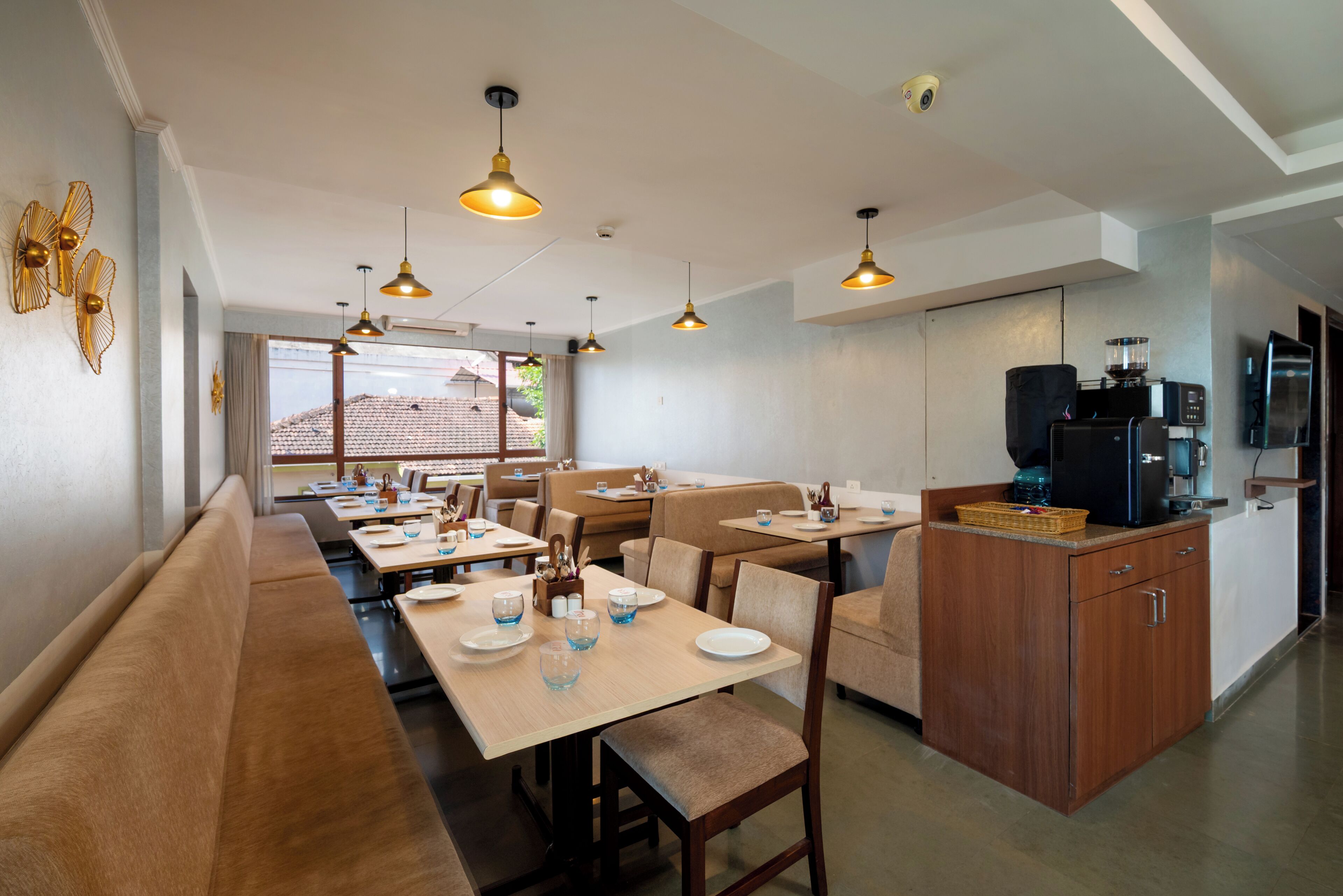 A dining area with multiple tables and benches, a kitchen area with appliances, and a view of the outdoors.