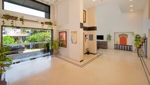 A spacious lobby with a high ceiling, large windows, and multiple potted plants. - Ira by Orchid, Porvorim, Goa (Porvorim)