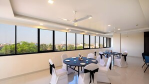 A conference room with round tables, white chairs, and black sashes. - Ira by Orchid, Porvorim, Goa (Porvorim)