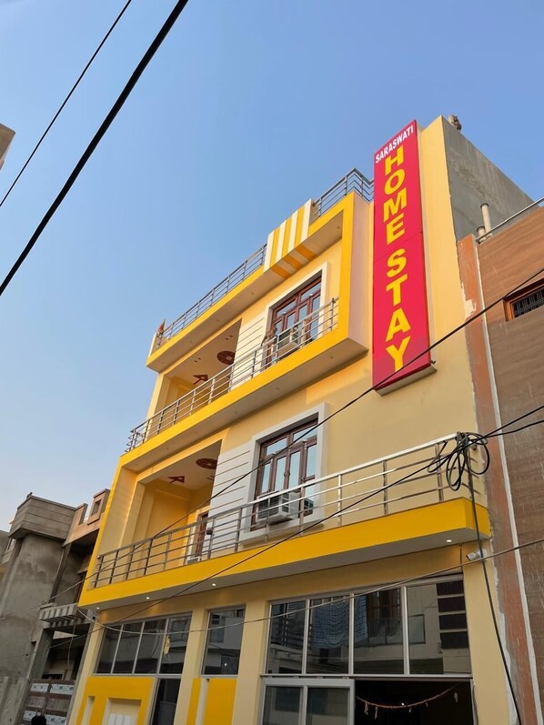 A multi-story building with a prominent red sign reading "Saraswati Home Stay". - Saraswati Luxurius Home Stay (Faizabad)