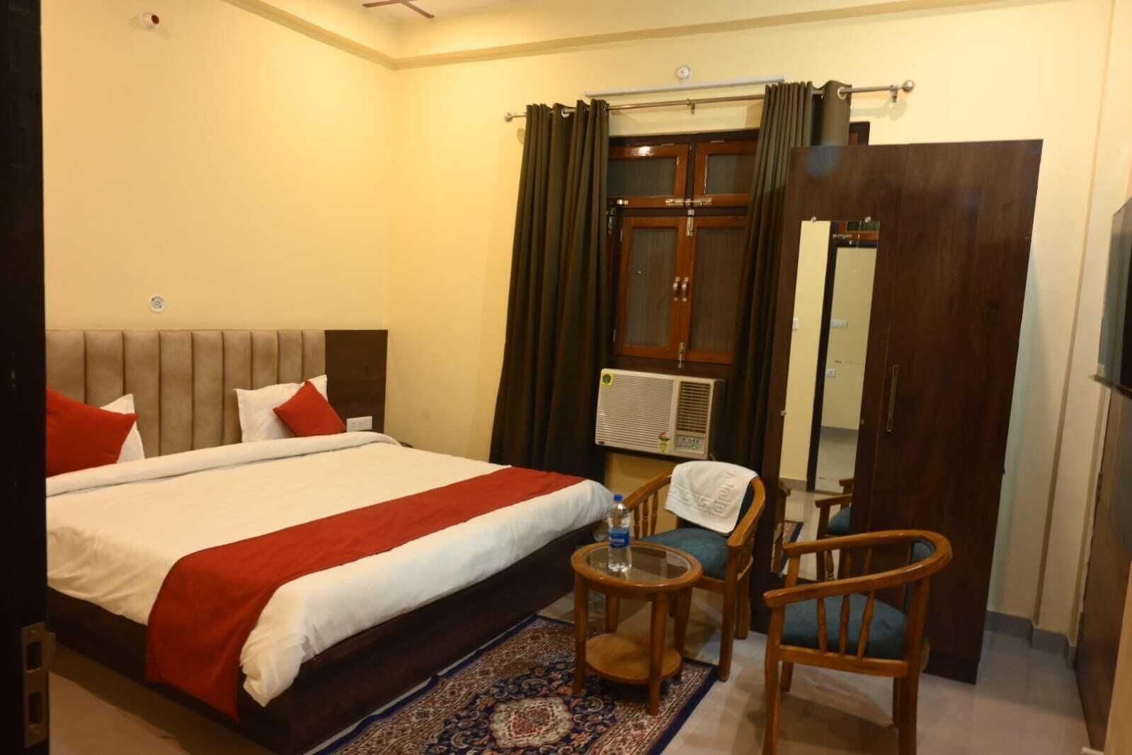 Une chambre d’hôtel avec un grand lit, une petite table avec une chaise, un miroir et une armoire.