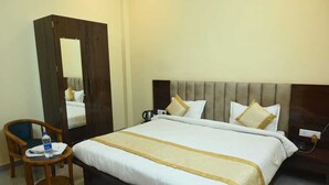 Habitación de hotel con una cama grande, una silla de madera, un escritorio y un espejo.