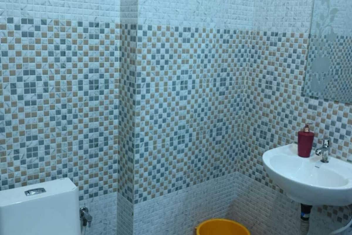 A bathroom with a toilet, sink, and yellow bucket.