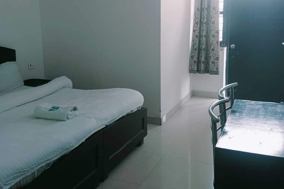 Una habitación de hotel con cama, escritorio y ventana con cortinas.
