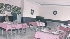 Comedor con mesas dispuestas para el servicio, una estatua y adornos en la pared.