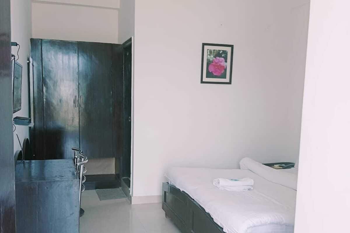 Un dormitorio con cama, armario, baño con ducha y ventilador de techo.