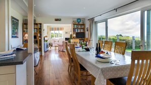 A dining area with a table set for four, a kitchen with wooden cabinets, and a view of the outdoors.