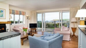 A spacious living room with a fireplace, a television, and a large window offering a scenic view.