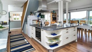 A modern kitchen with a central island, a dining area with a view, and a cozy seating area.