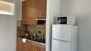 Una cocina con armarios de madera, un lavamanos de acero inoxidable, un microondas y un refrigerador.