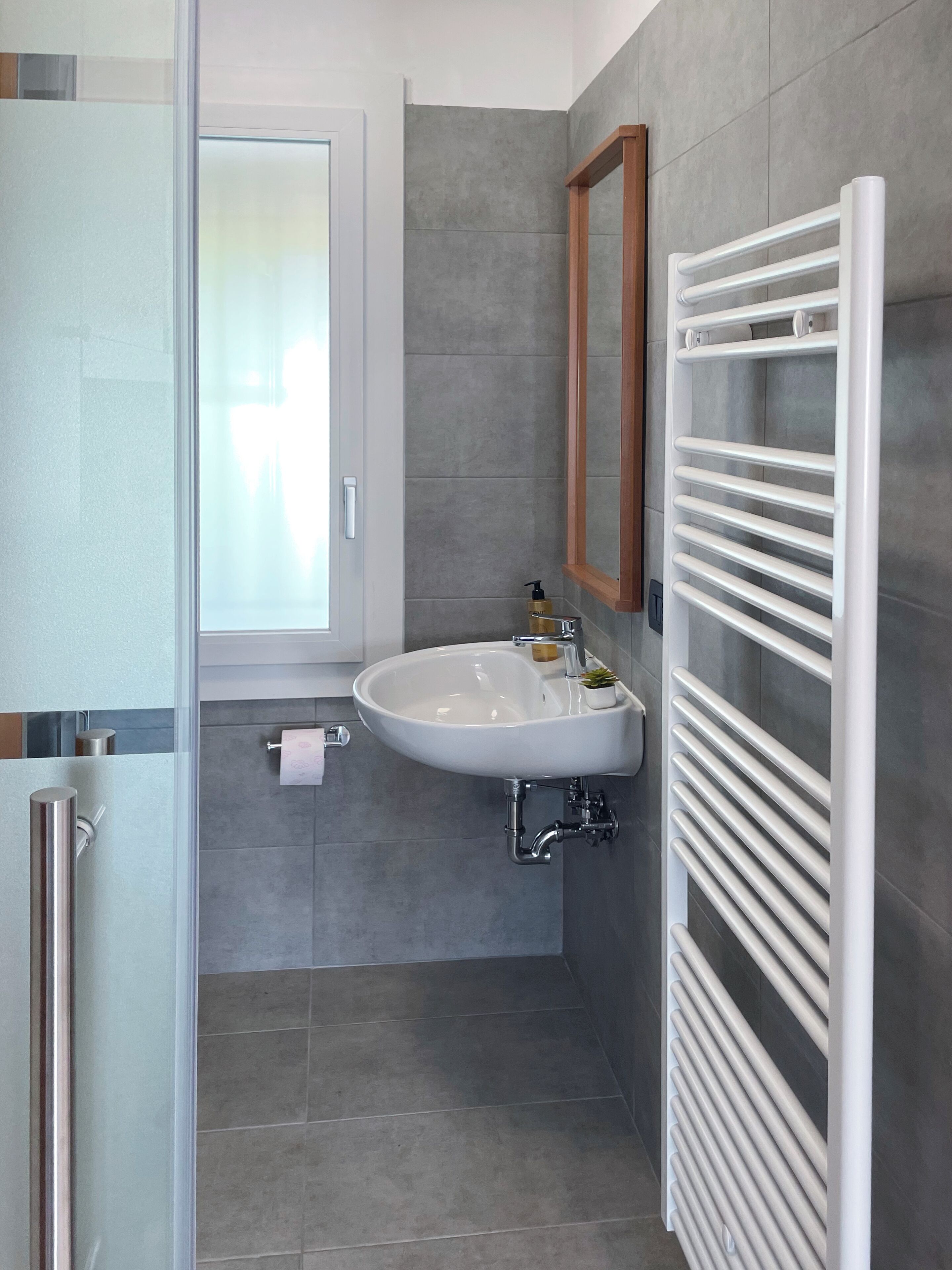 Une salle de bain moderne dotée d’une douche à parois de verre, d’un lavabo blanc et d’un porte-serviettes intégré.