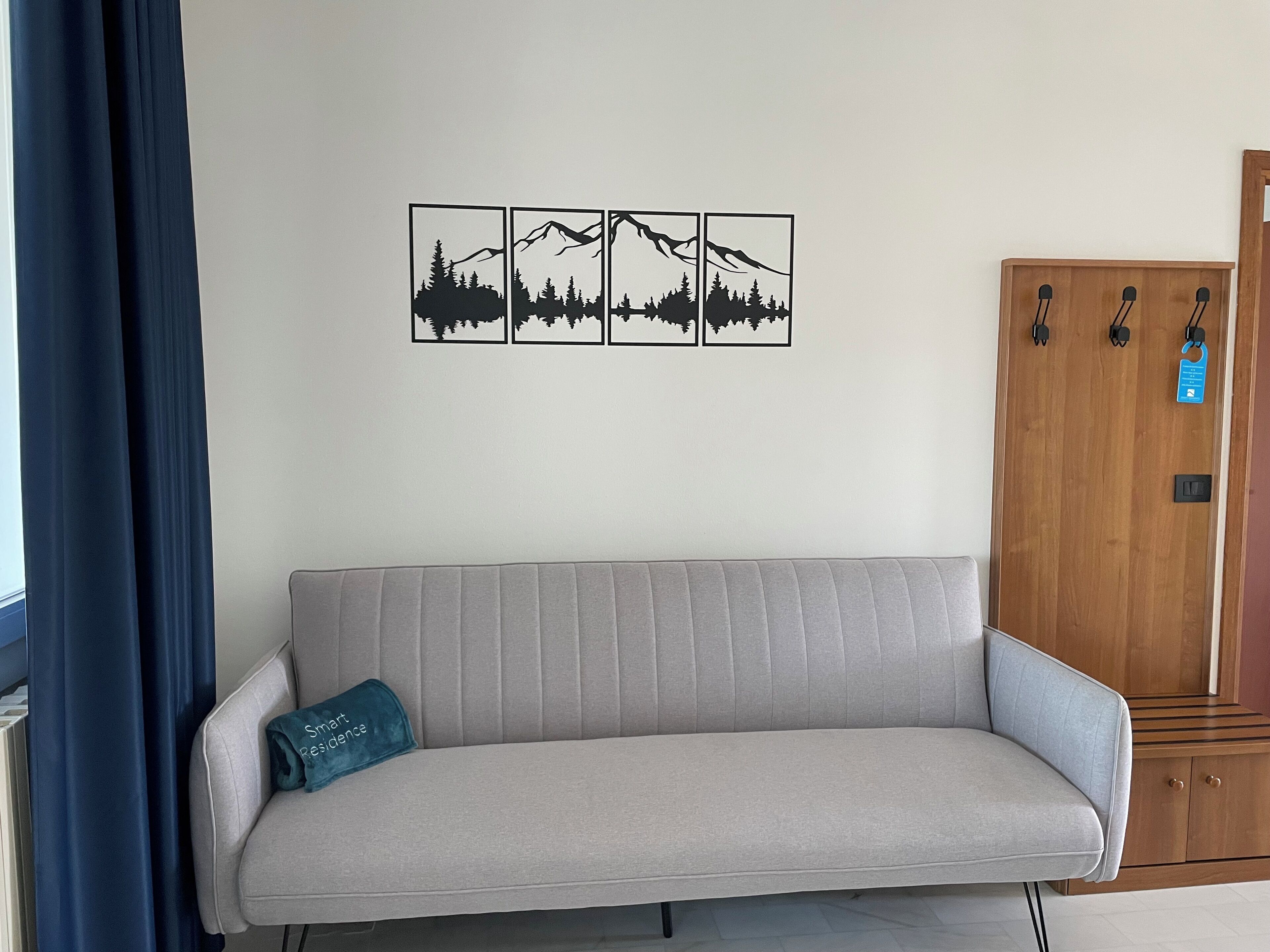 A room with a grey sofa, a wooden cabinet, and a wall with four framed pictures.