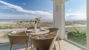 A balcony with a table and chairs overlooking a beach. - Apartamentos Azul (Castelldefels)