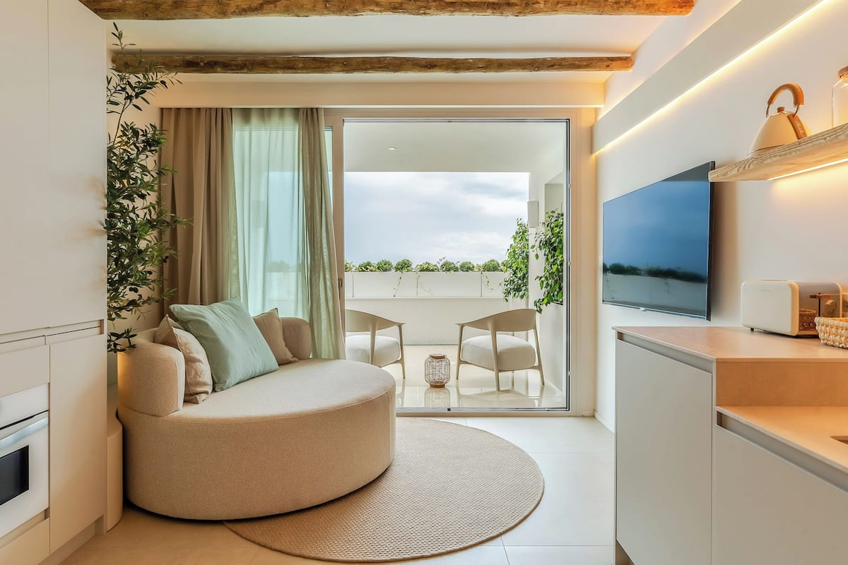 Una sala de estar moderna con un sofá curvo, un televisor de pantalla plana y una zona de comedor con sillas.