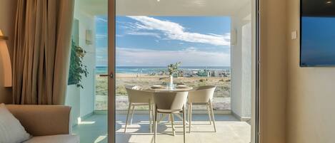 A modern room with a sliding glass door leading to a balcony with a view of the beach and ocean.