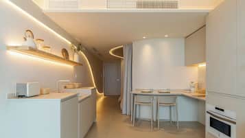 Une cuisine moderne dotée d’appareils électroménagers intégrés, un coin repas avec une petite table et des chaises, et un plafond au design incurvé.