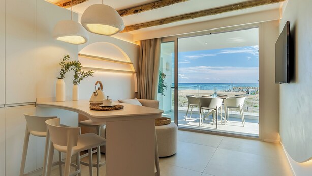 A modern kitchen with a dining area, large windows, and a view of the beach. - Apartamentos Azul (Castelldefels)
