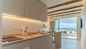 A modern kitchen with a large island, built-in appliances, and a view of the beach. - Apartamentos Azul (Castelldefels)