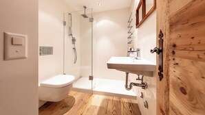 A modern bathroom with a glass-enclosed shower, a white sink, and a wooden cabinet. - Residence Au Reduit - Living in the Heart of St. Moritz (San Maurizio)