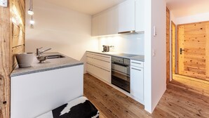 A modern kitchen with white cabinets, a built-in oven, and a wooden floor. - Residence Au Reduit - Living in the Heart of St. Moritz (San Maurizio)