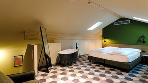 Habitación de hotel con cama, bañera, espejo y pared verde.