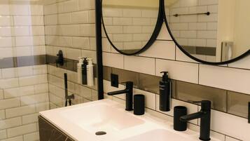 Une salle de bain moderne avec un lavabo blanc, des robinets noirs et un grand miroir.