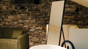Un baño moderno con una bañera independiente, una pared de piedra y un sofá verde.