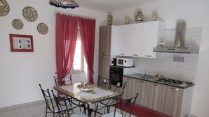 Una cocina con una mesa de comedor, sillas, microondas, estufa y armarios.