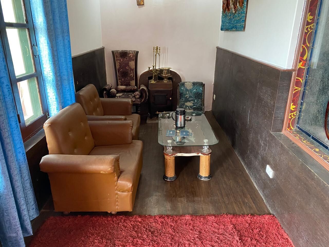 A living room with a brown leather sofa, a glass coffee table, and a red rug.