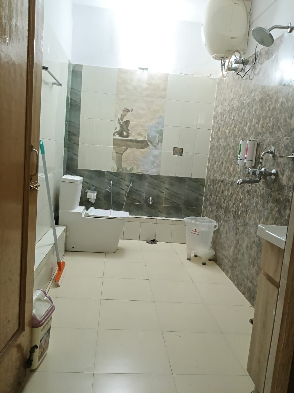 Et badeværelse med badekar, toilet og bruser.