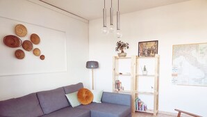 Un salon moderne avec un canapé d’angle gris, une table basse en bois, une bibliothèque en bois et une carte accrochée au mur.