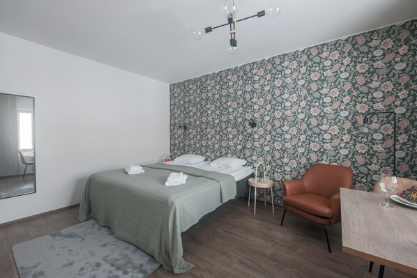 Una camera da letto con un letto, una sedia, un tavolino e uno specchio.