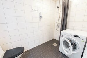 Un bagno piccolo con il WC, una lavatrice e una doccia.