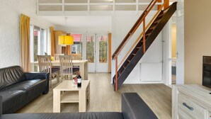 A spacious living area with a sofa, dining table, and a staircase.
