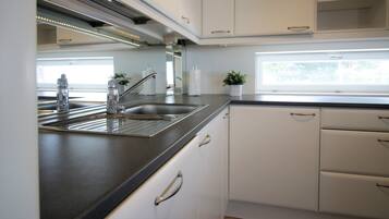 Una cocina moderna con un lavamanos de acero inoxidable, armarios blancos y una ventana que ofrece luz natural.