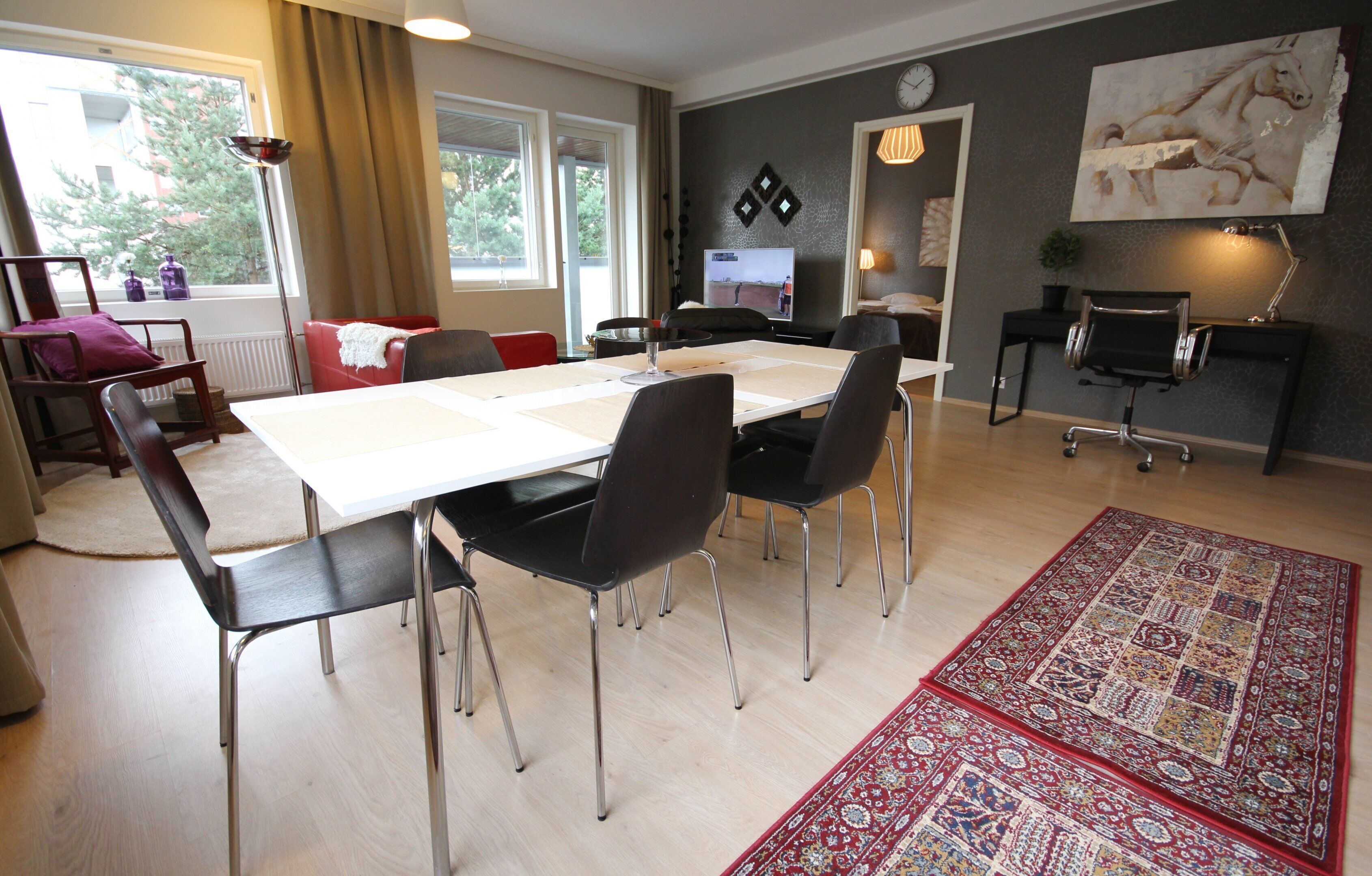 A modern living room with a dining area, a TV, and a large painting on the wall.