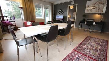 A modern living room with a dining area, a TV, and a large painting on the wall.