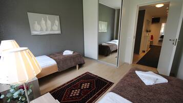 Una habitación de hotel con dos camas, una mesita de noche con lámpara, una alfombra y un espejo.