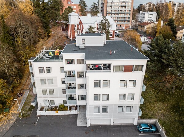 A multi-story building with balconies, a parking area, and surrounding trees. - Forenom Apts Espoo Leppävaara (Espoo)