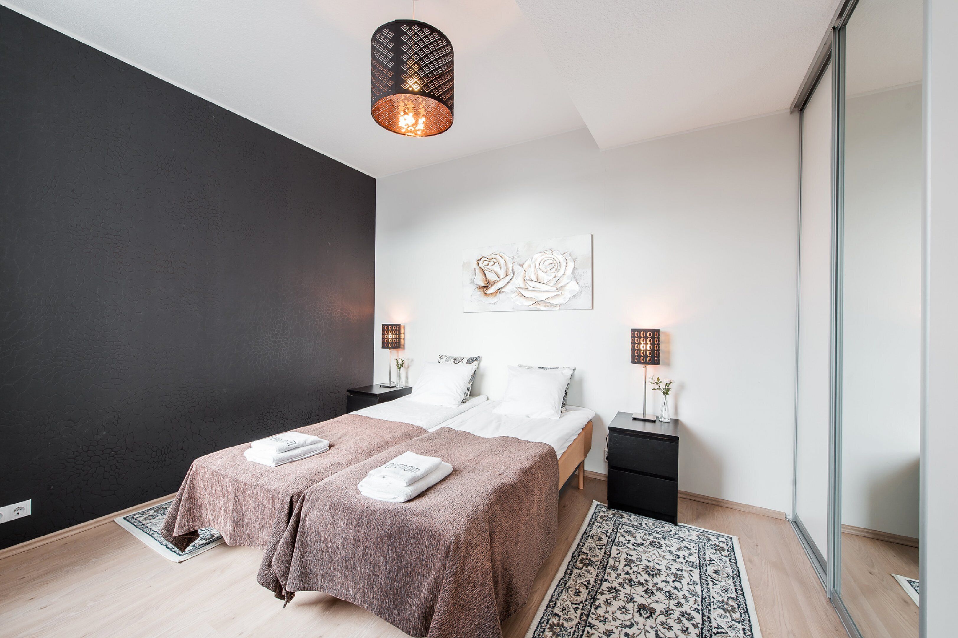 Una camera da letto moderna con un letto grande, abat-jour, un tappeto e un quadro appeso al muro.