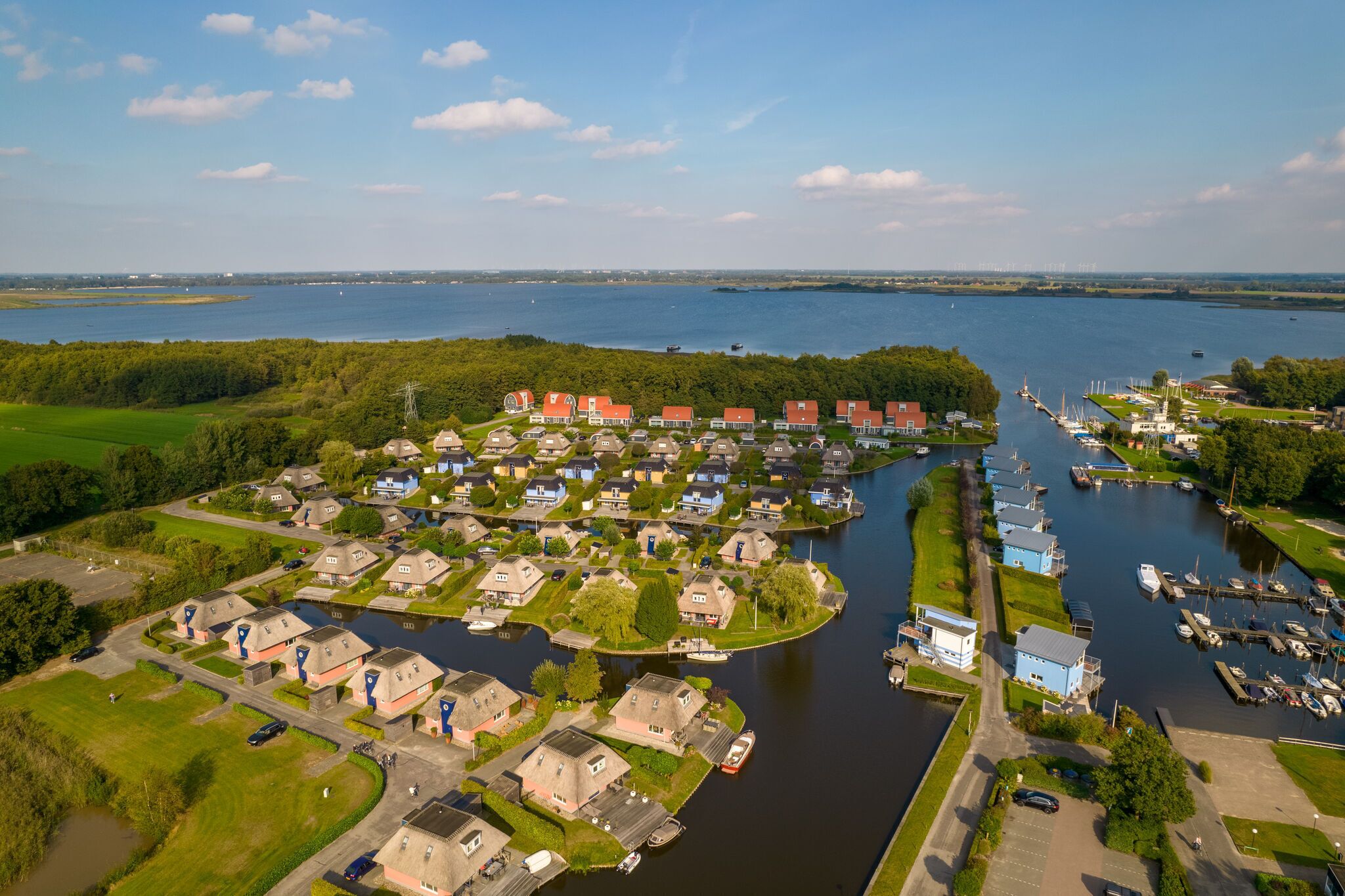 An aerial view of a lakeside residential area with houses, a marina, and boats.