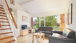 Una sala de estar moderna con una escalera de madera, un sofá, una mesa de centro y un televisor.