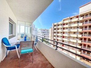 Varanda com mesa, cadeiras e vista para edifícios próximos.