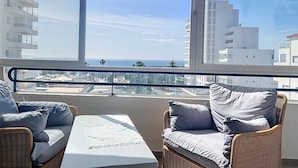 Ein Balkon mit Korbmöbeln und Blick auf das Meer und die Stadt.