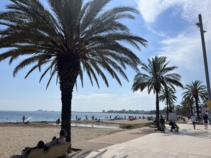 A beach with palm trees, a promenade, and a view of the sea. - Gran Canal - Apartamento visto al mar, 50 M de la (Rosas / Roses)
