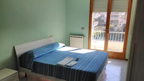 Un dormitorio con cama, radiador y balcón.