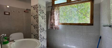A bathroom with a bathtub, a sink, and a window with a view of greenery.