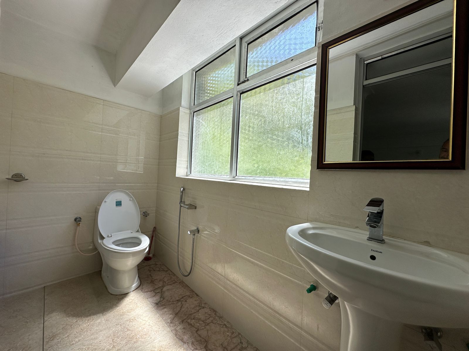A bathroom with a toilet, a sink, and a window.