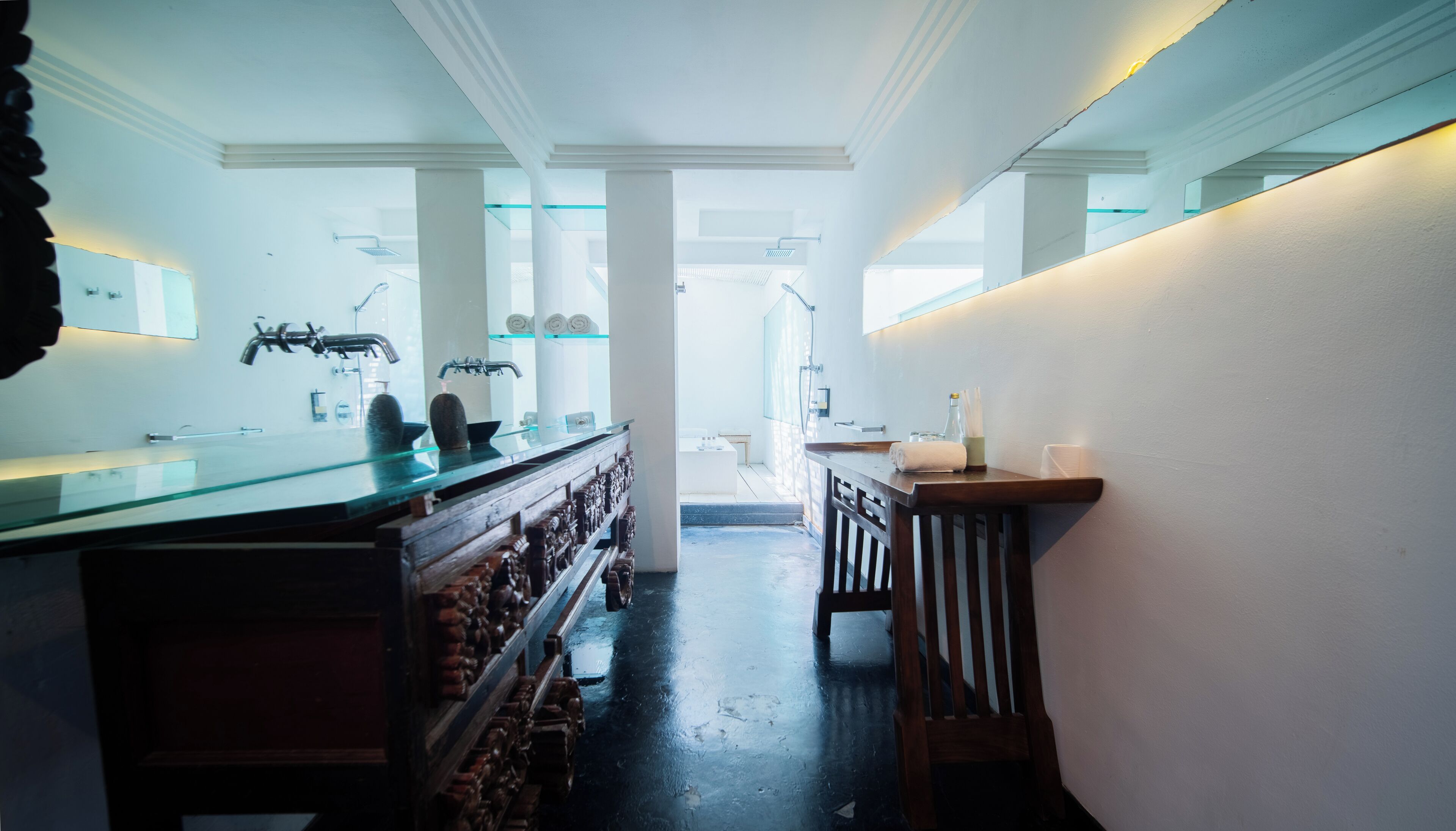 A modern bathroom with a large glass-enclosed shower, a wooden vanity, and a mirror above the sink.