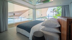 A modern bedroom with a large bed, a view of the ocean, and a balcony with a view of the beach. - Morabito Art Villa (Tibubeneng)